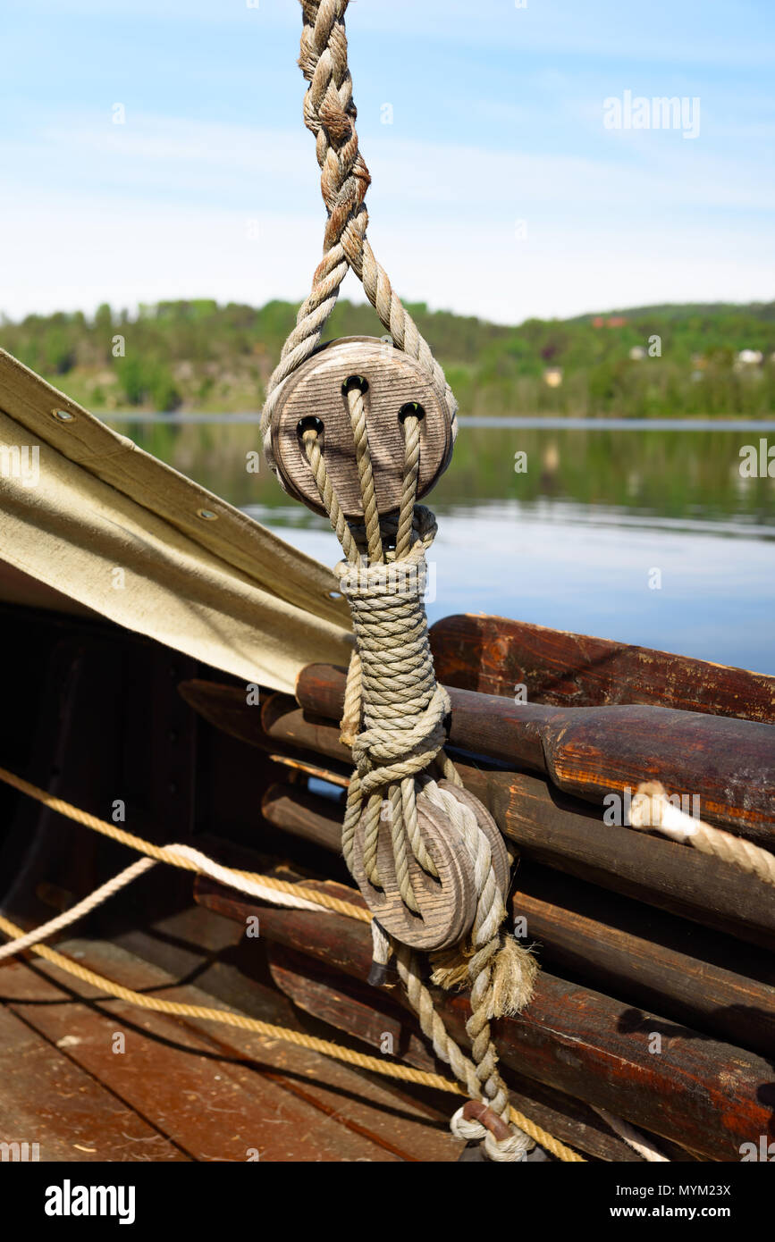 Well used wooden oars and ropes on a Viking ship replica. Coastland in the background. Stock Photo