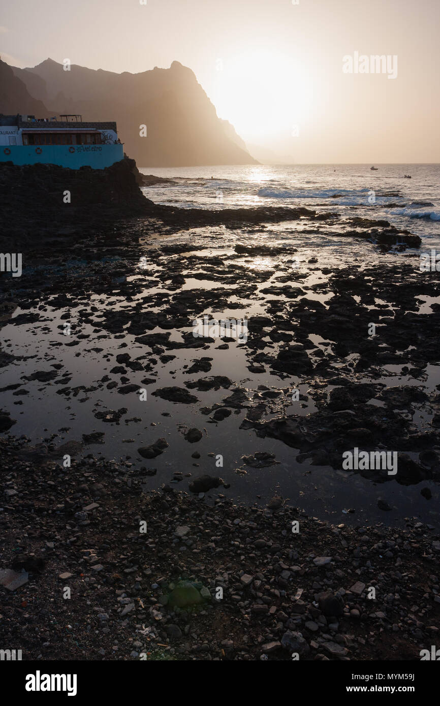 PONTA DO SOL, CAPE VERDE - DECEMBER 08, 2015: Beautiful sunset evening at the rocky shore of Santo Antao Island. Veleiro restaurant, mountains and the Stock Photo