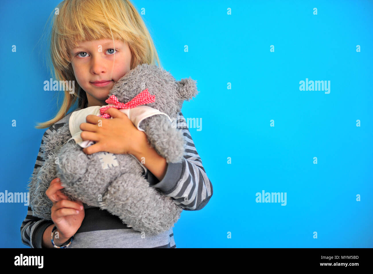 Smiling boy hugging teddy bear at blue wall Stock Photo - Alamy