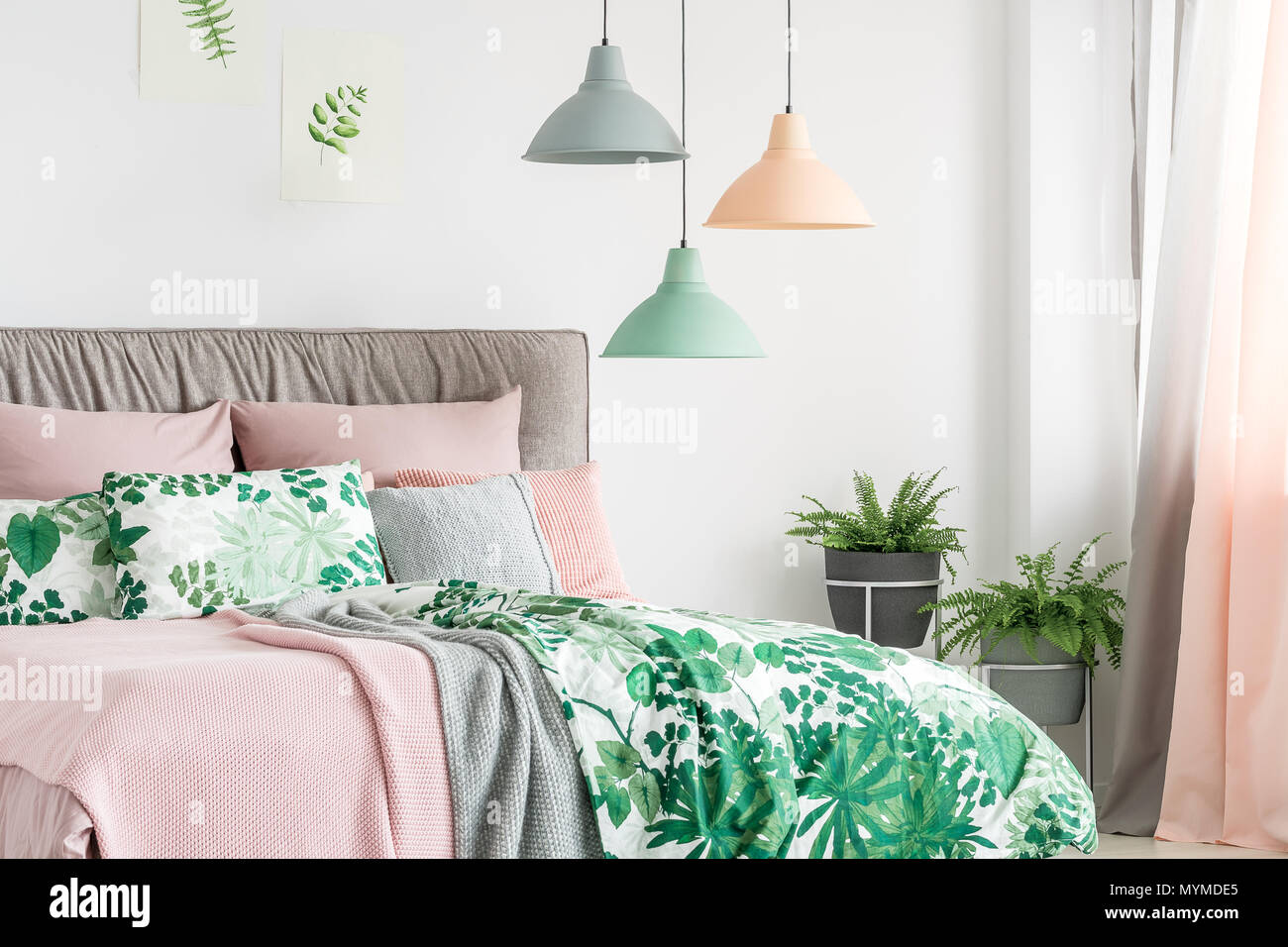 Three lamps in pastel colors hanging above bed with soft bedhead in bright interior Stock Photo