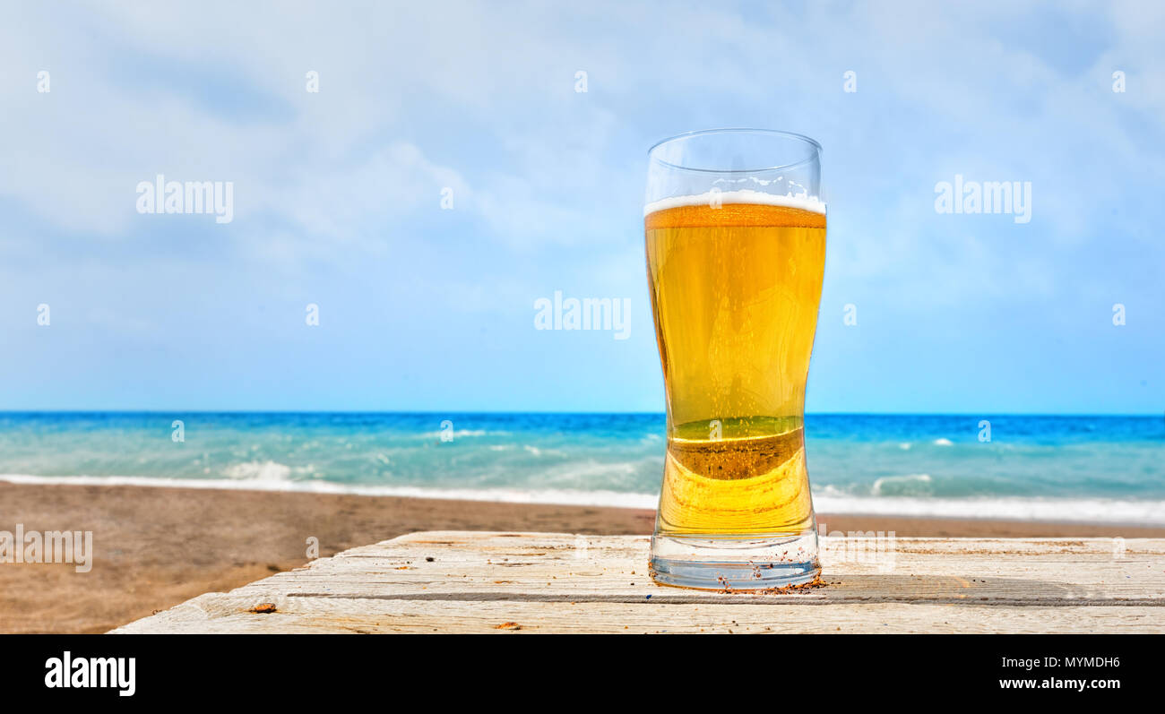 Glass of pale golden Pilsner lager at the seaside standing on a rustic