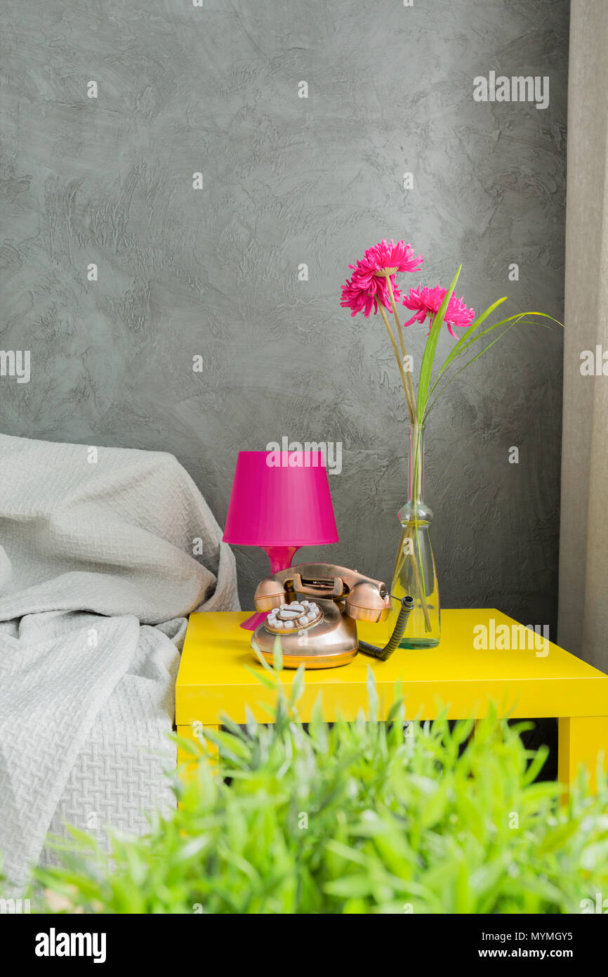 Image of a grey interior with sofa, yellow coffee table and pink lamp