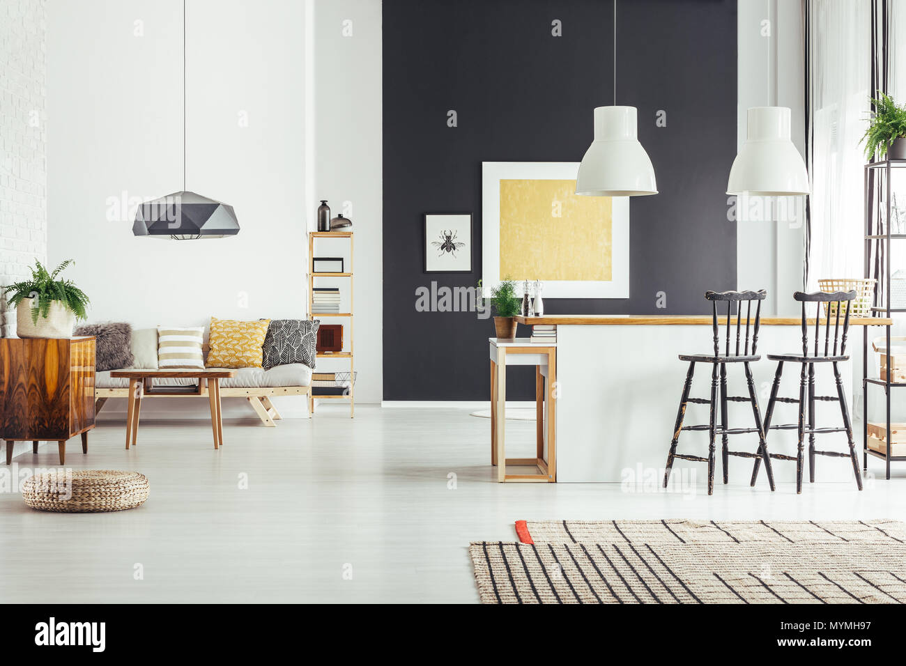 Gold painting on black wall in spacious room with kitchen island and patterned pillows on sofa Stock Photo