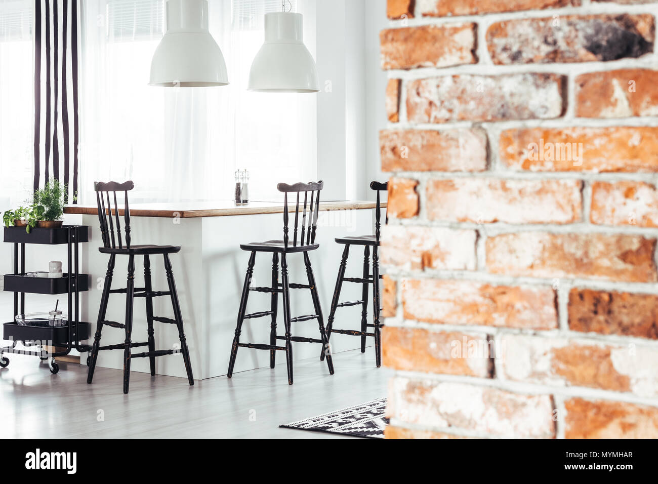 Red brick wall in rustic dining room with white lamps above countertop