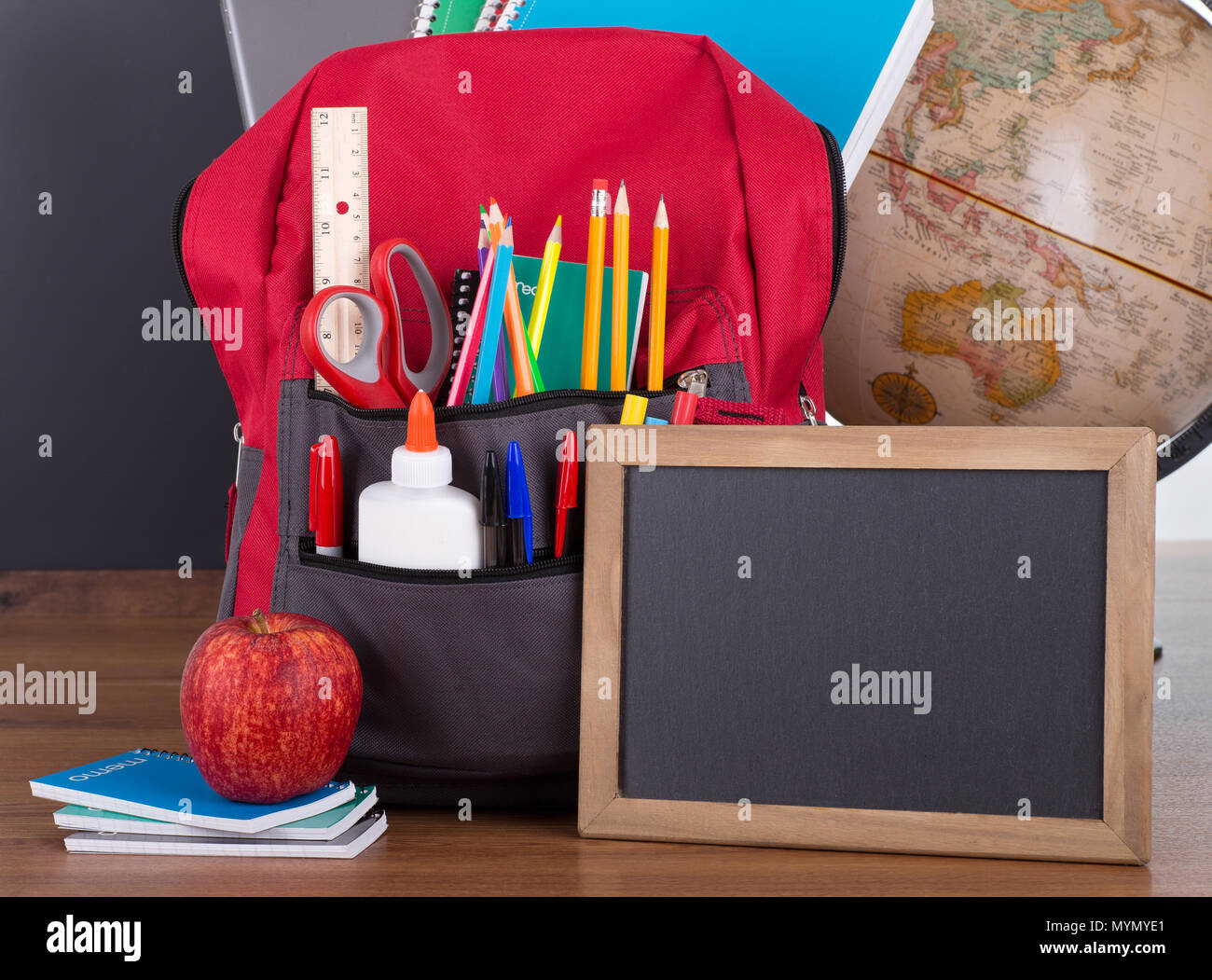 Closeup of a book bag with an assortment of school supplies on a blackboard background Stock Photo Alamy