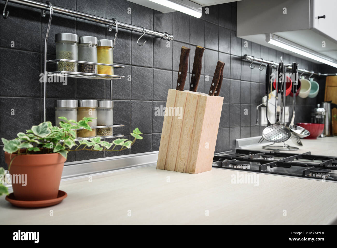 Kitchen utensils and jars of spices in hanging shelf in modern