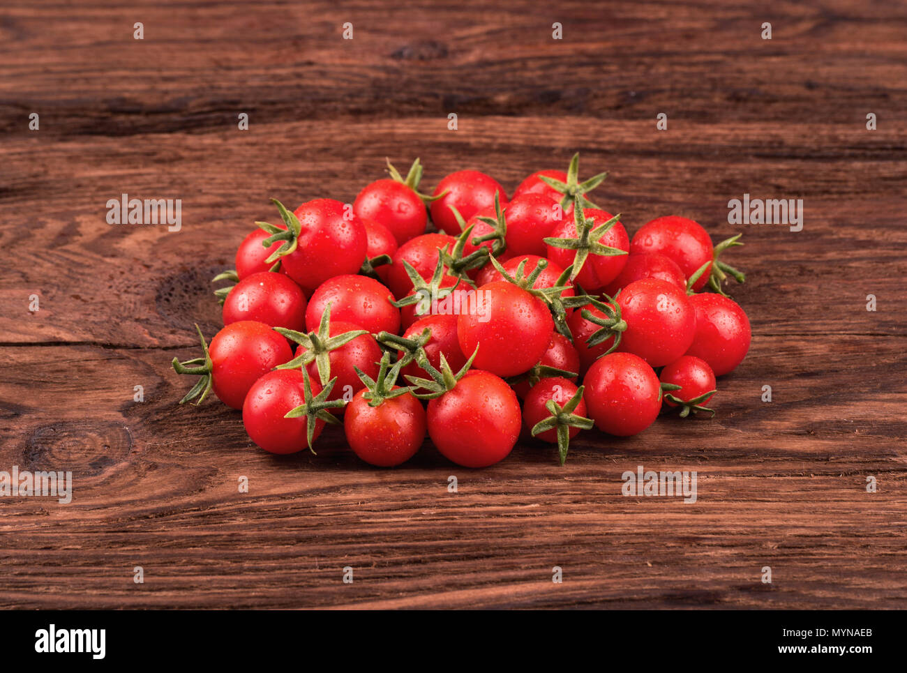Pile of fresh small red cherry tomatoes on a wooden background Stock ...