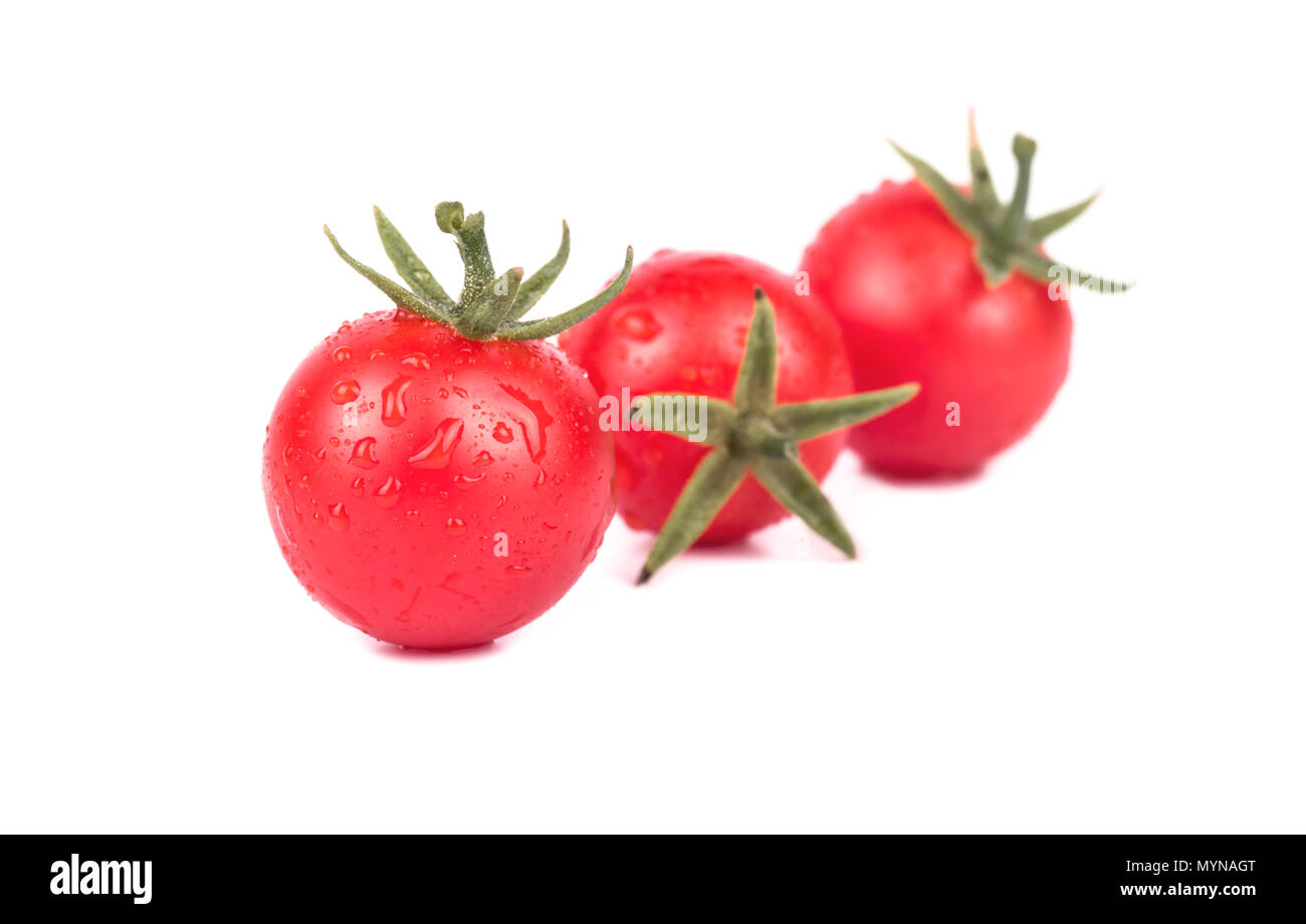 Three fresh small red cherry tomatoes with drops on a white background ...