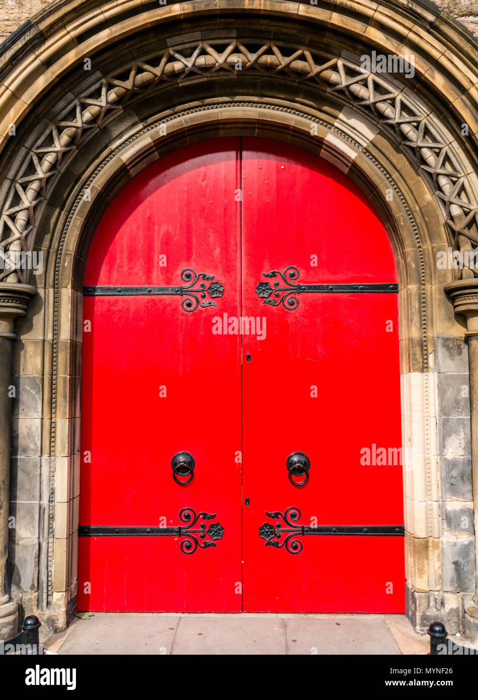 Bright red ornate arched door with elaborate hinges, Mansfield Traquair Centre, SCVO headquarters, Edinburgh, Scotland, UK Stock Photo