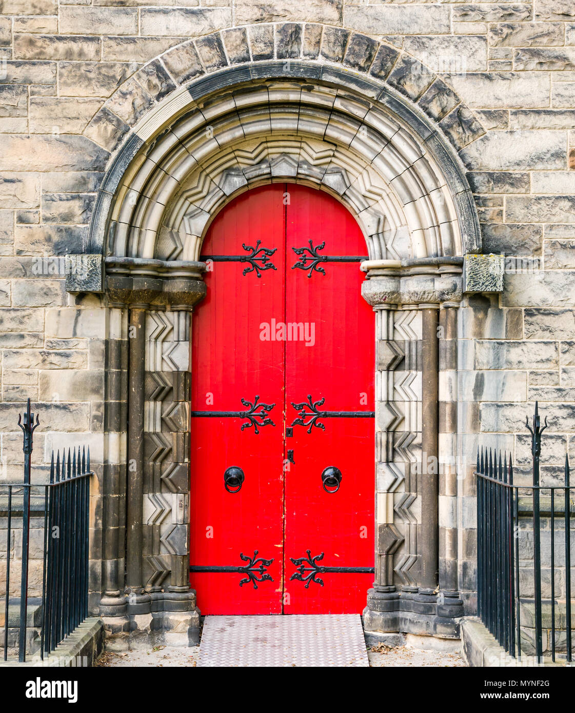 Bright red ornate arched door with elaborate hinges, Mansfield Traquair Centre, SCVO headquarters, Edinburgh, Scotland, UK Stock Photo