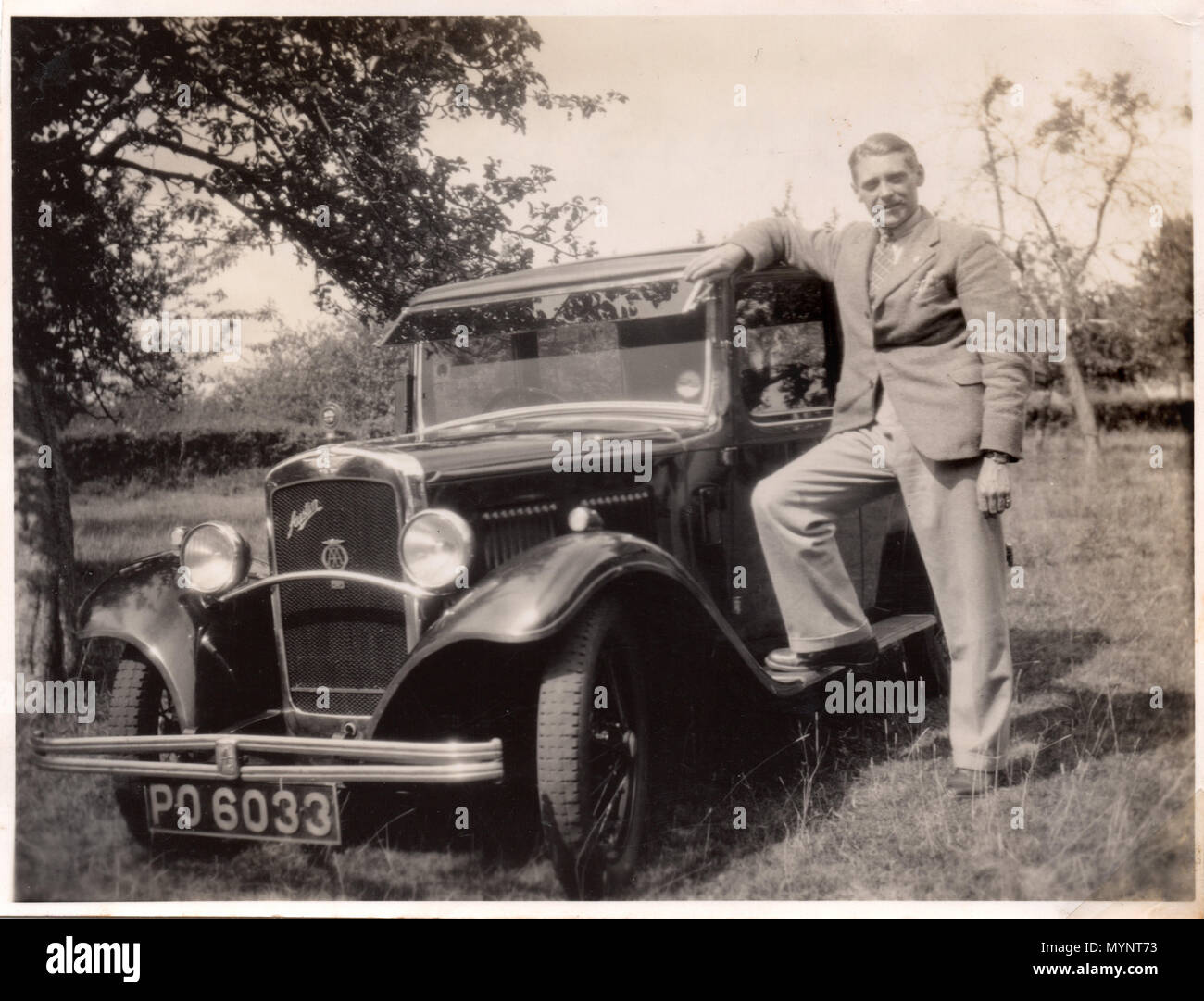 Proud owner shows off his new Austin 10/4 - in a field!  Photograph made circa 1935 Stock Photo