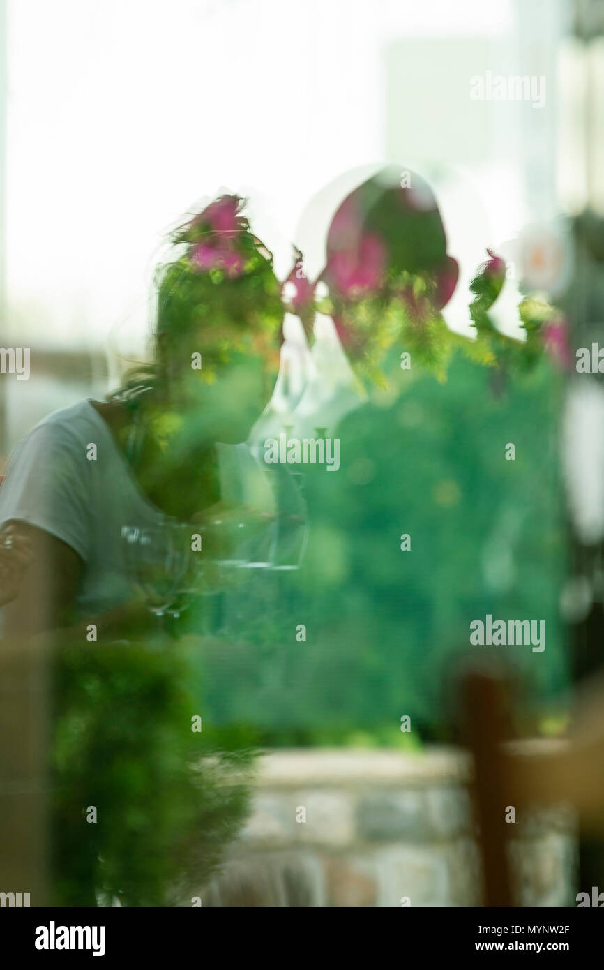 Through the window pane, couple in love, plant reflections in the pane. Stock Photo
