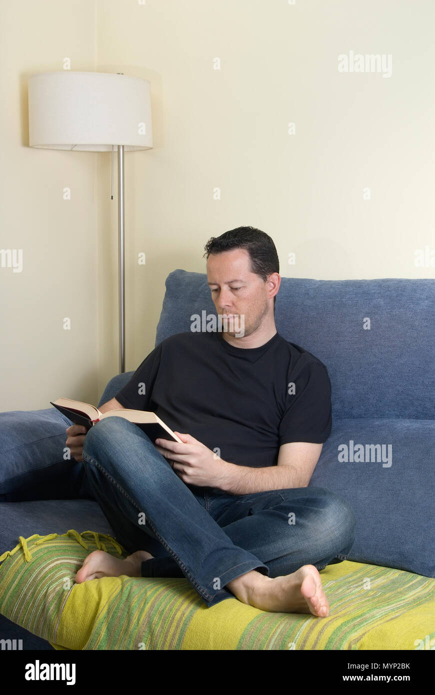 Teen on a sofa reading a book Stock Photo Alamy