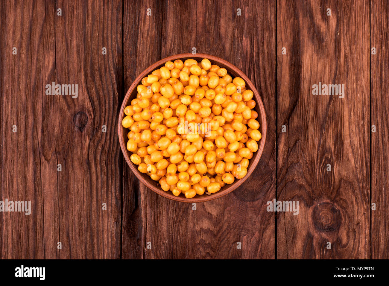 Full bowl of fresh berries of sea-buckthorn on a wooden background top view Stock Photo