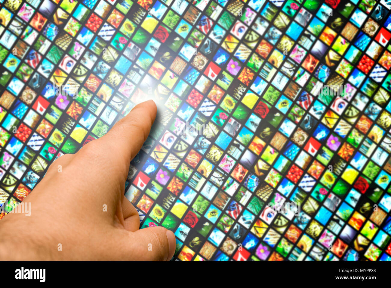 male hand touching with the finger a wall of multiple colorful video screens, concept for digital broadcasting or internet television Stock Photo
