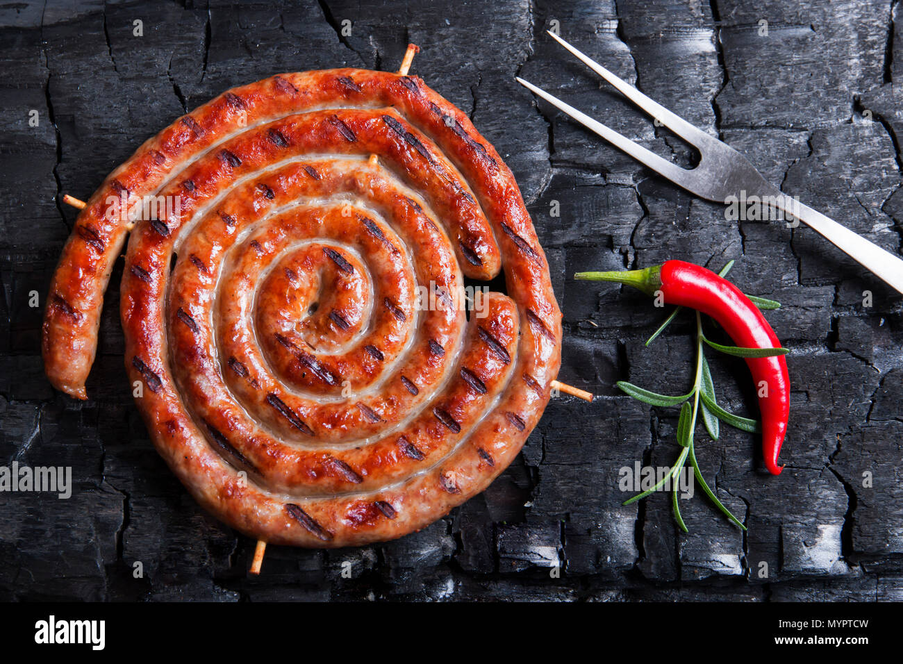 Grilled spiral sausages on a black background of charcoal Stock Photo