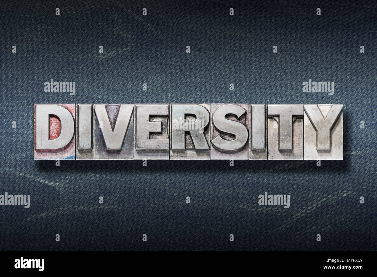 diversity word made from metallic letterpress on dark jeans background Stock Photo