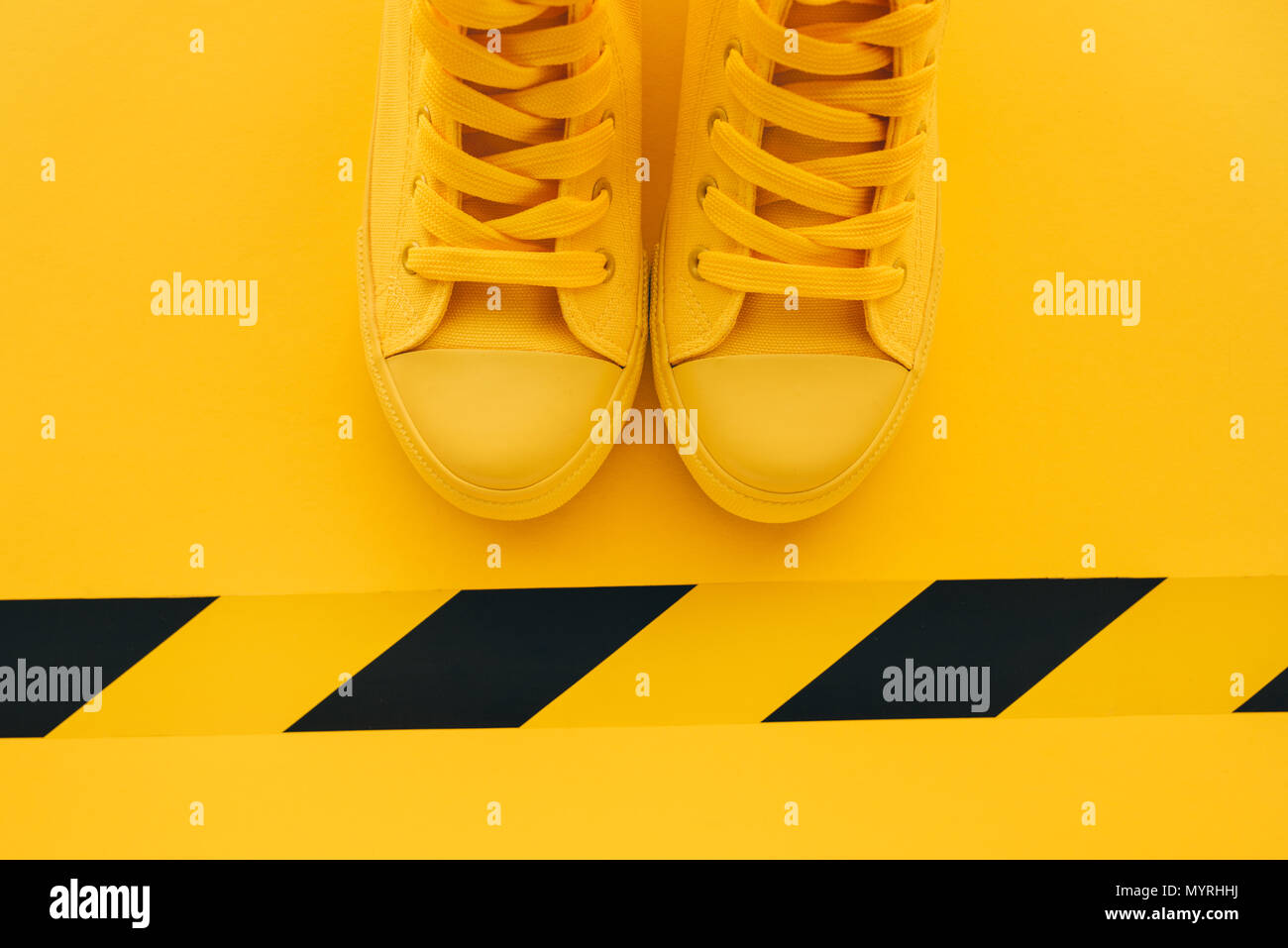 First in line young man queueing, conceptual overhead top view image of yellow sneakers waiting in line Stock Photo