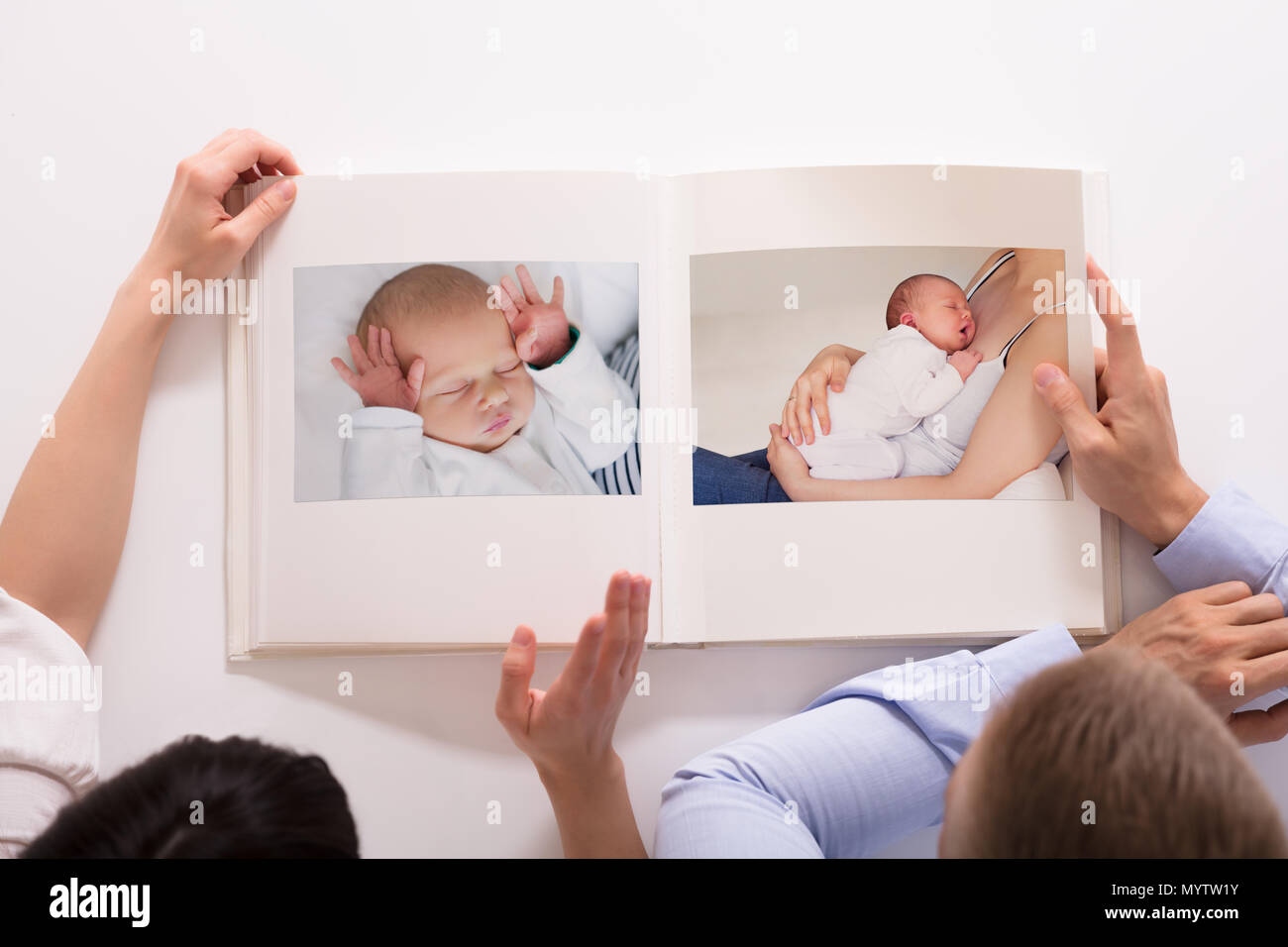 elevated view of couple looking at babys photo album on white baby album background
