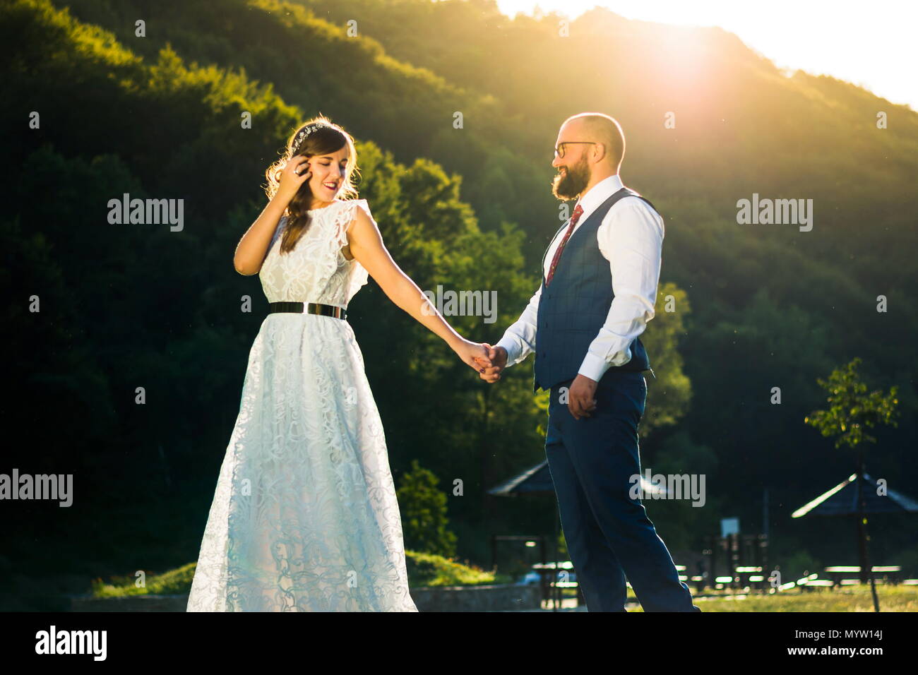 Bride and groom holding hands at romantic sunset Stock Photo - Alamy