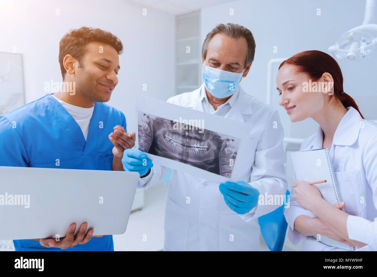 Attentive doctor standing between two interns Stock Photo - Alamy