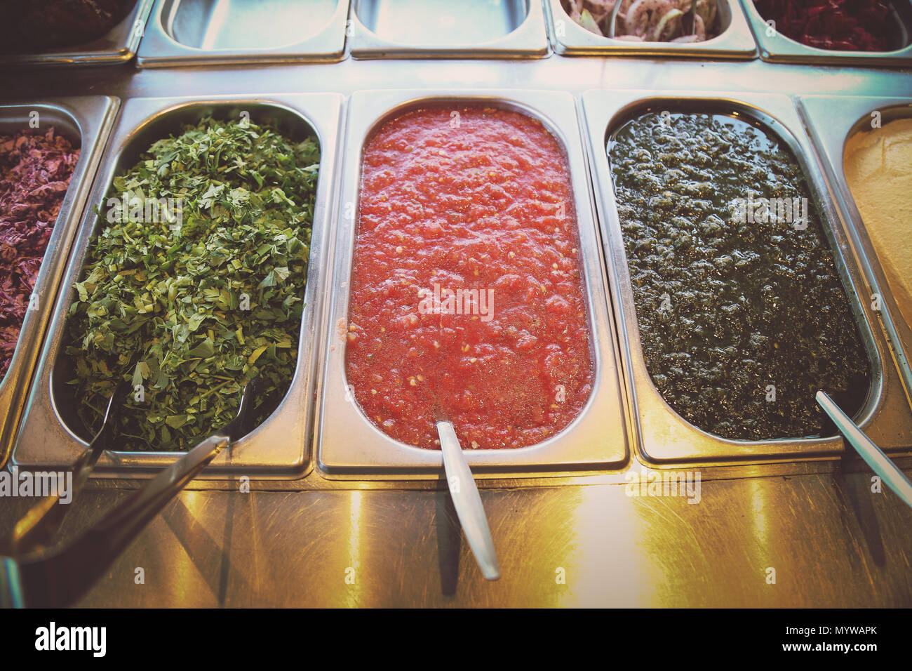 A buffet style bar with selection of food and salad with serving