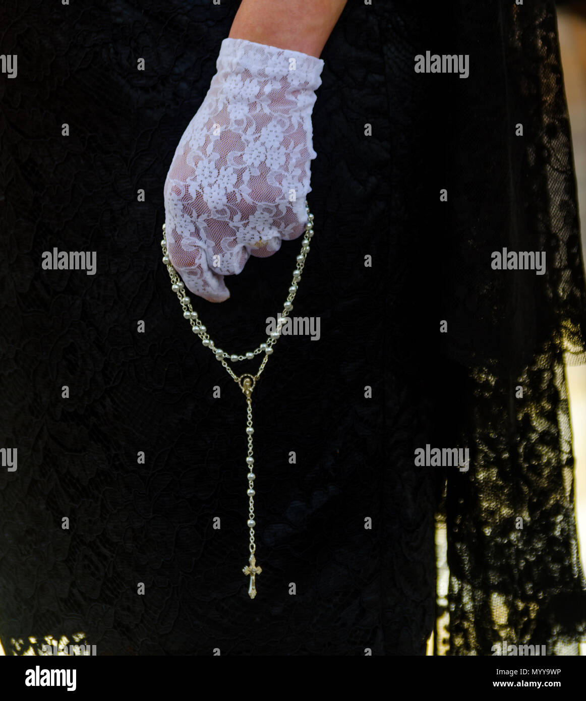 rosary-held-by-a-woman-in-a-black-dress-and-white-gloves-symbol-of