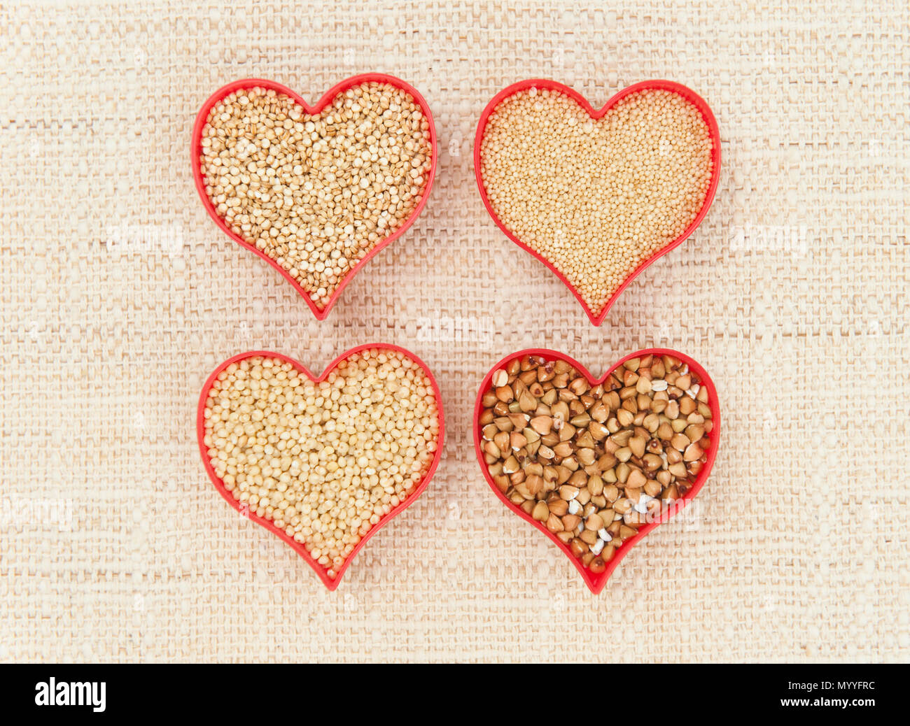 Four red hearts filled with health super seeds quinoa, millet, amaranth and buckwheat on canvass Stock Photo