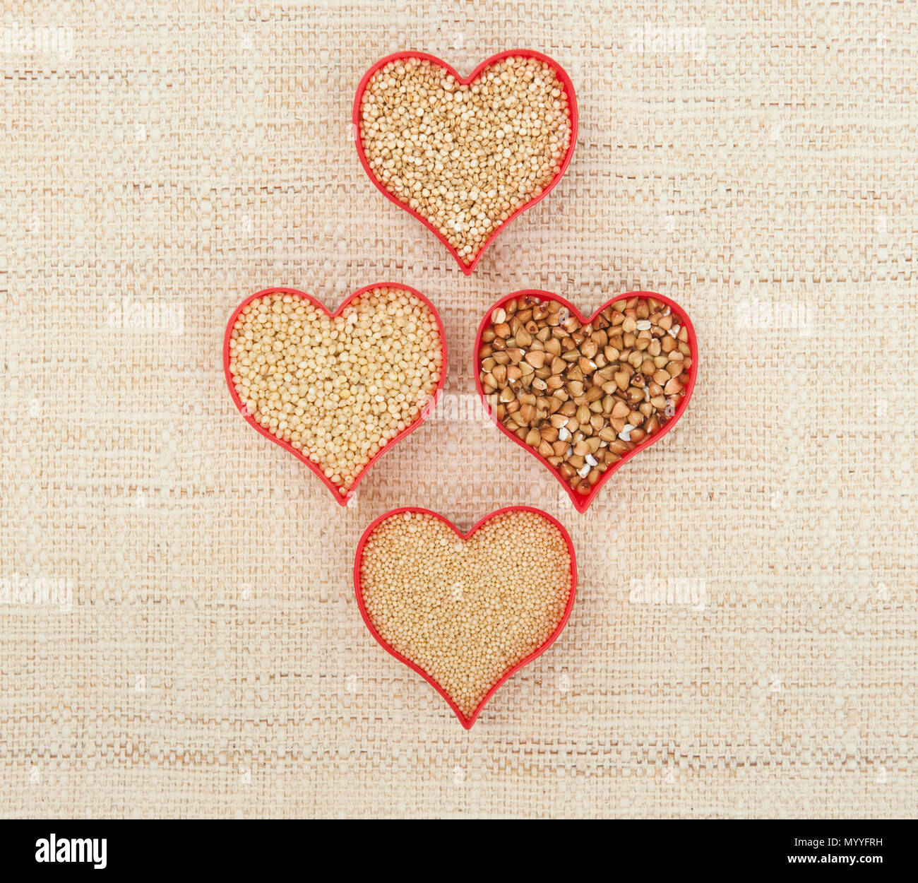 Four red hearts filled with gluten-free seeds quinoa, millet, amaranth and buckwheat on canvass Stock Photo