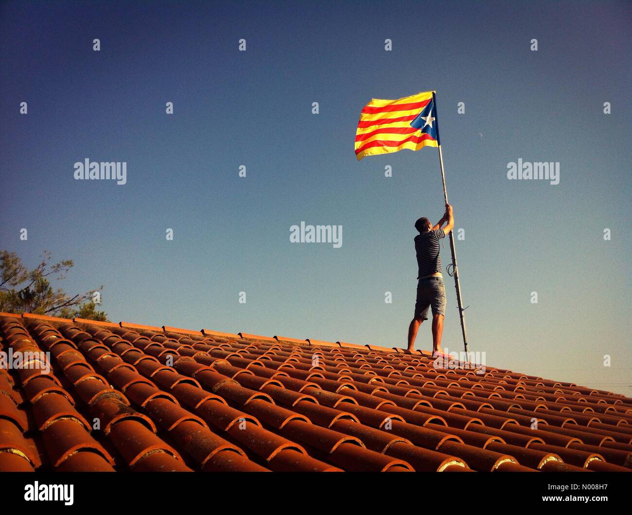 Llerona, Spain. 8th September, 2016. In the village of Llerona (30 kms from Barcelona, Spain), a man fixes a estelada flag (sign of catalan independentism) atop of his house on 8th Sept. 2016, two days before of Catalonia National Day. Credit:  Jobopa / StockimoNews/Alamy Live News Stock Photo