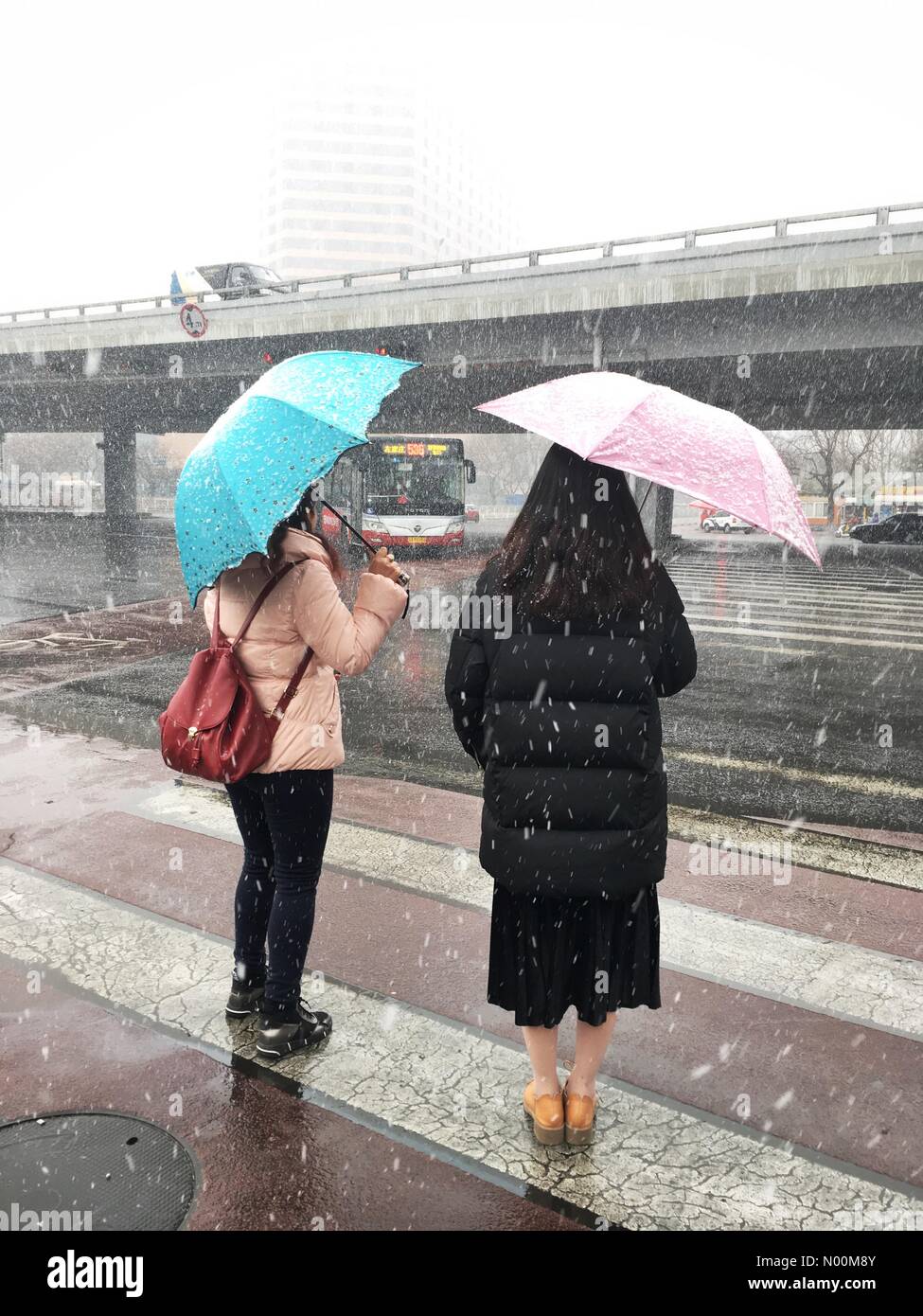 85 Chaoyang Qu, Beijing Shi, China. 17th Mar, 2018. Beijing, China- March 17, 2018: First snowy day in Beijing, China (Chaoyang district) sins winter 2016. Two girls with umbrellas at the intersection. Credit: Irkin09/StockimoNews/Alamy Live News Stock Photo
