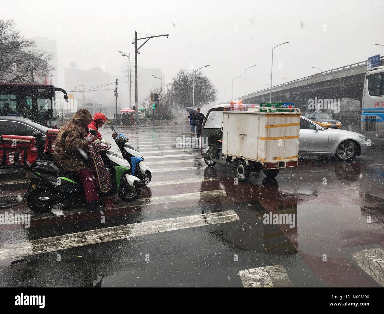 Beijing, China- March 17, 2018: First snowy day in Beijing, China (Chaoyang district) since winter 2016. Road intersection with electric scooters, trucks and cars. Credit: Irkin09/StockimoNews/Alamy Live News Stock Photo