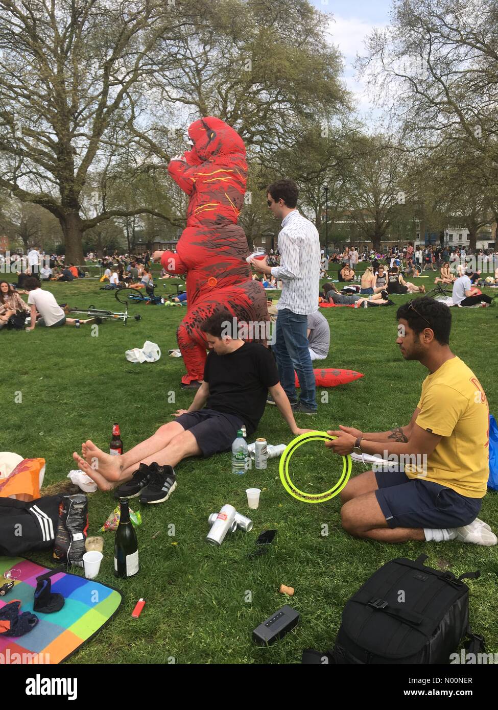 London, UK. 21st April 2018. Man in dinasour outfit jokes with people as Londoners enjoying sunny warm weather in London field Credit: Emin Ozkan/StockimoNews/Alamy Live News Stock Photo