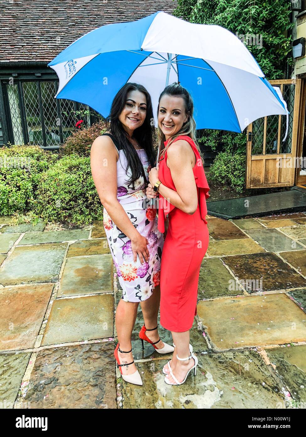 Bordon, UK. 27th July, 2018. UK Weather: Heavy rainfall in Churt. Cain Manor, Churt. 27th July 2018. Thundery showers moved across the south east this afternoon. Abbie and Amy sheltering from the rain at a wedding in Churt, Hants Credit: jamesjagger/StockimoNews/Alamy Live News Stock Photo