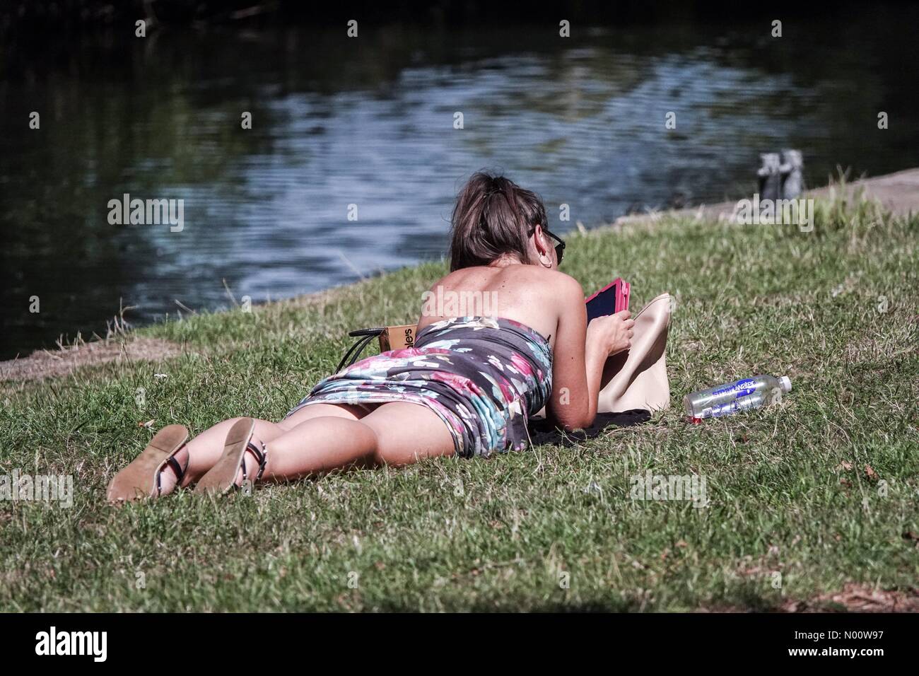 UK Weather: Hot and sunny in Godalming. Woolsack Way, Godalming. 03rd August 2018. Heatwave conditions across the south east today. A young lady reading by the River Wey in Godalming. Credit: jamesjagger/StockimoNews/Alamy Live News Stock Photo