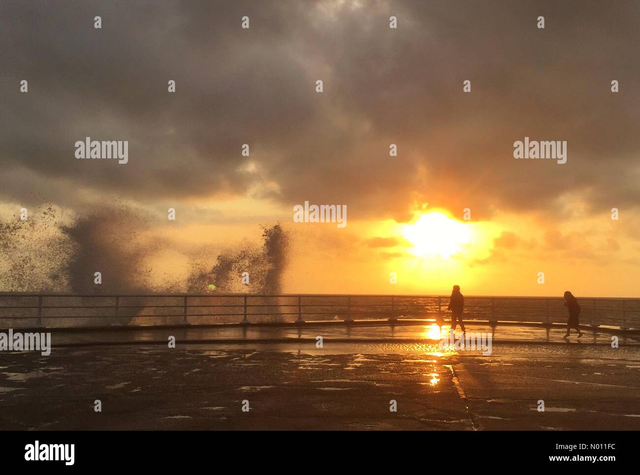 Aberystwyth Wales UK. Sunday 02 June 2019. Children silhouetted as they play in the spray of crashing waves on Aberystwyth promenade at sunset on a windy evening Credit: keith morris1/StockimoNews/Alamy Live News Stock Photo