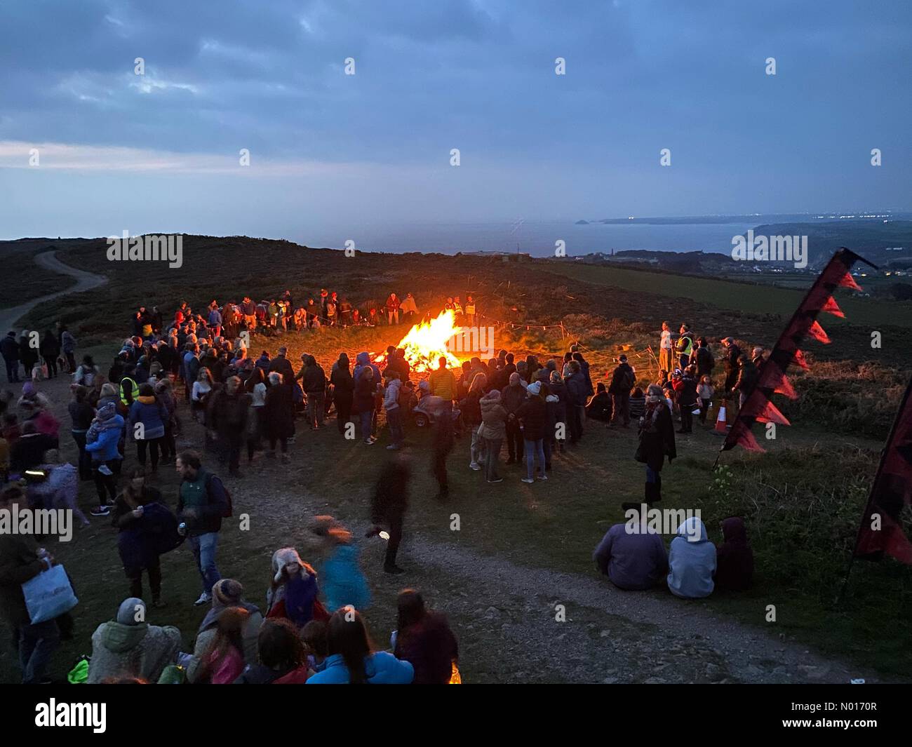 St Agnes, Cornwall, UK. 30th April 2022. Pilgrims crowd atop the beacon at bonfire lighting ceremony high above the town during annual Bolster festival at St Agnes in Cornwall, UK. 30th April, 2022. Credit nidpor/ Alamy Live News Stock Photo