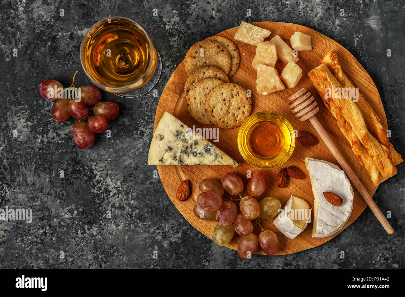 Assortment of cheese with wine, honey, nuts and grape on a cutting board, top view Stock Photo