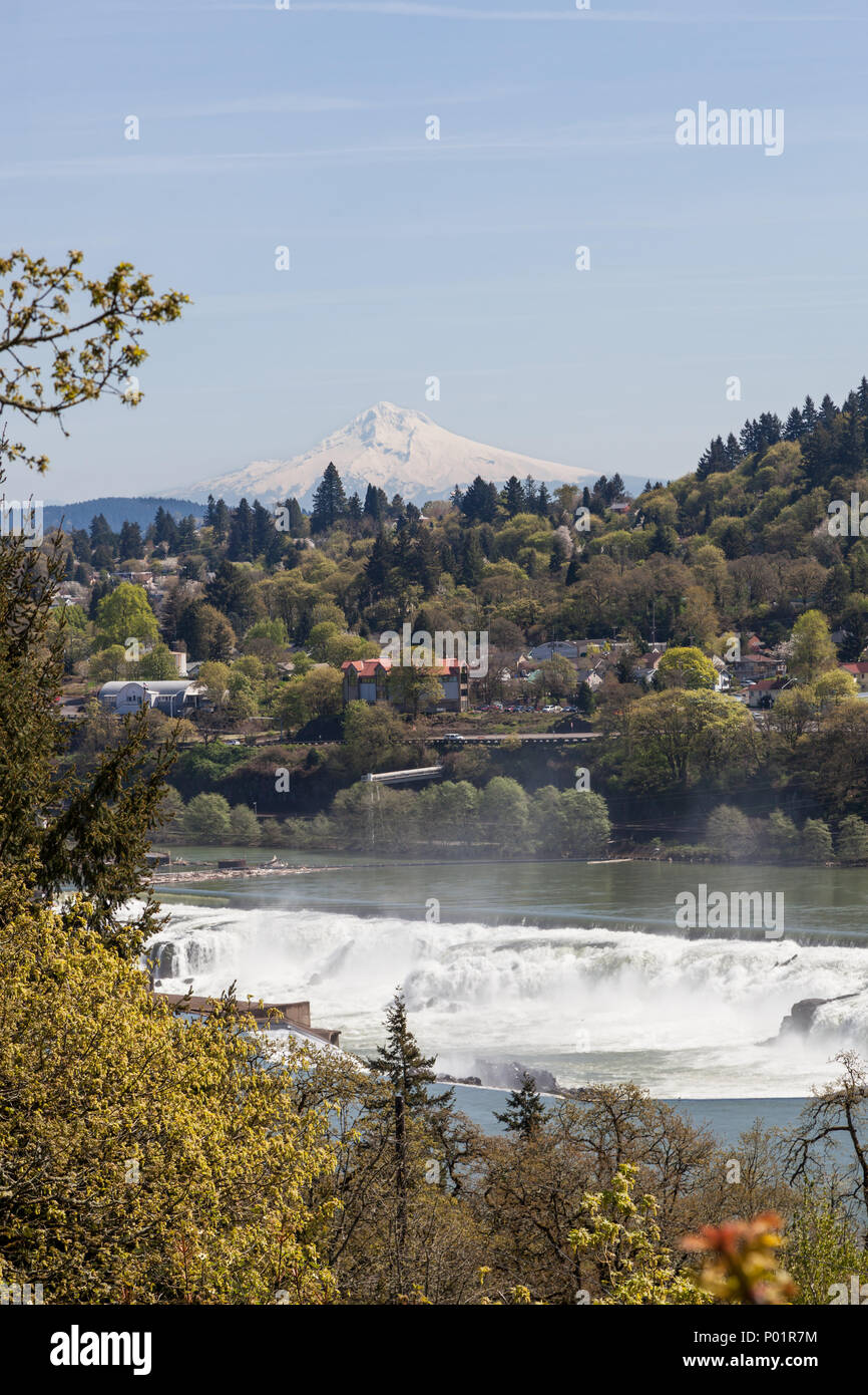 The Willamette River cascading over the rocks of Willamette Falls with Oregon City and Mt. Hood in the distance. Stock Photo