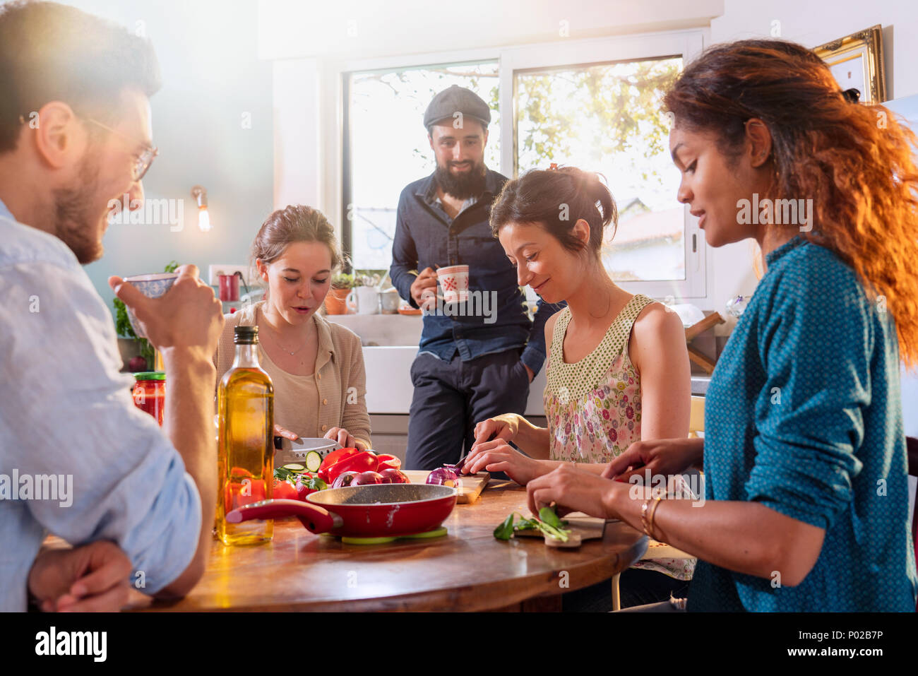 Multi-ethnic group of friends cooking lunch in the kitchen.  Stock Photo