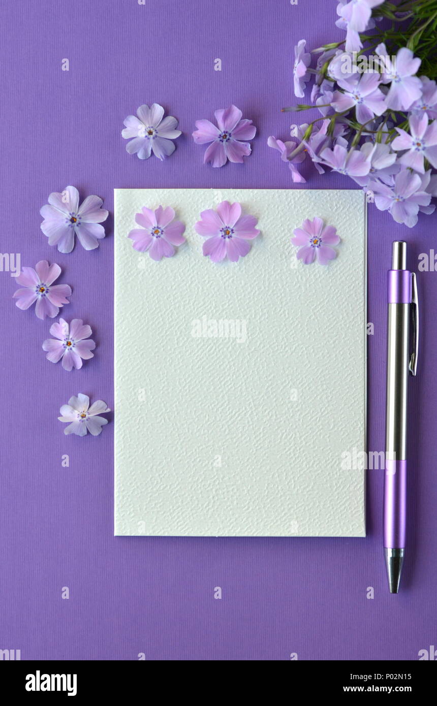 Ultra violet flatlay of feminine stationery, notebook, pen, lavender phlox flowers with copy space. Brainstorming ideas, note taking or diary writing Stock Photo