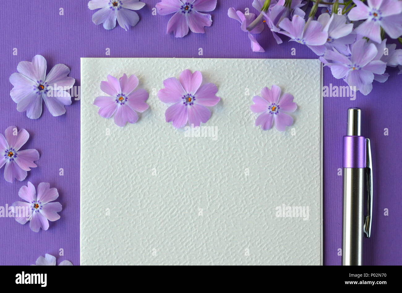 Ultra violet flatlay of feminine stationery, notebook, pen, lavender phlox flowers with copy space. Brainstorming ideas, note taking or diary writing Stock Photo