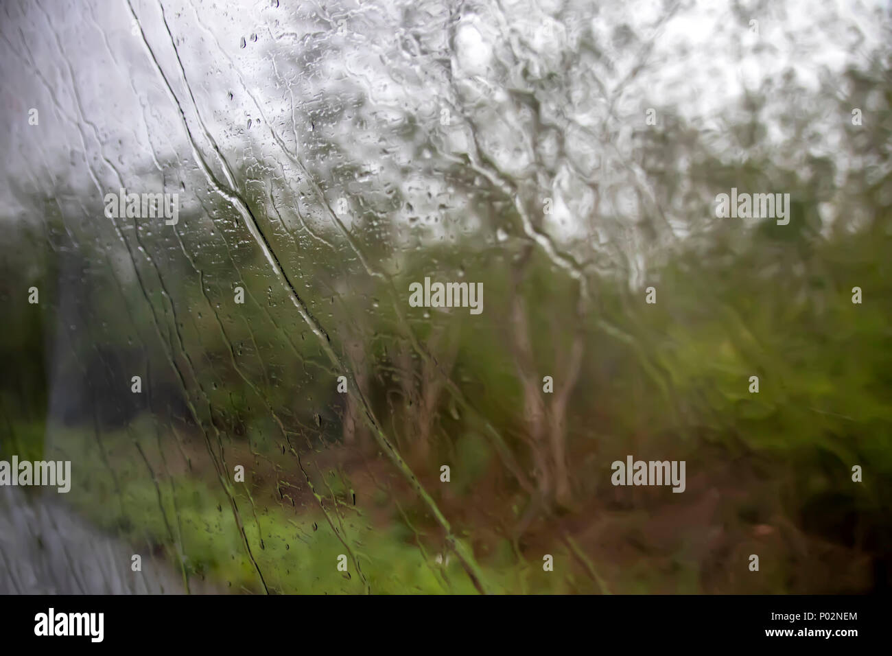 Streams of rain flow down on the window surface. Stock Photo