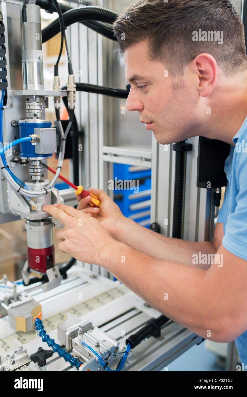Male Engineer Working On Machine In Factory Stock Photo