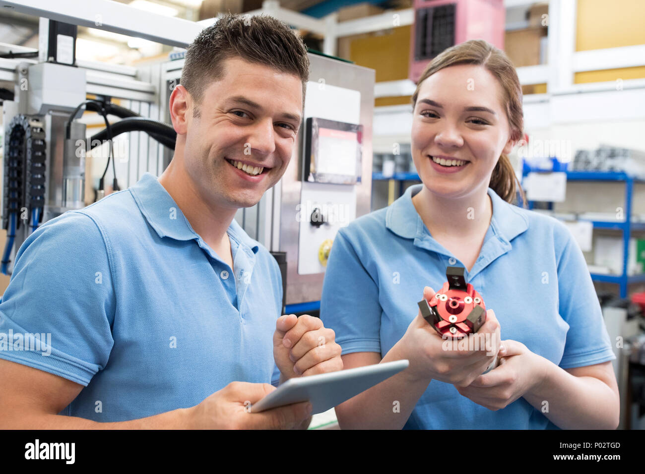 Portrait Of Engineer And Apprentice Examining Component In Factory Stock Photo