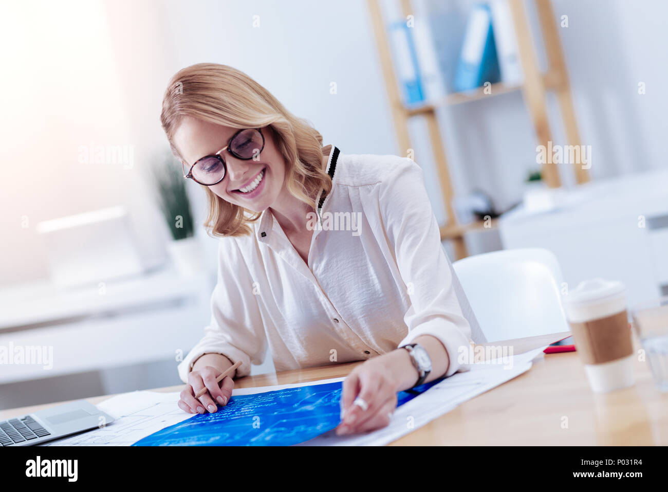 Happy delighted woman looking at the blueprint Stock Photo - Alamy