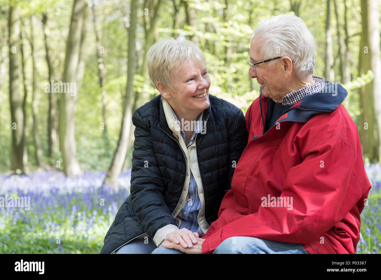 Loving Senior Couple Taking Break On Walk Through Bluebell Wood Stock Photo