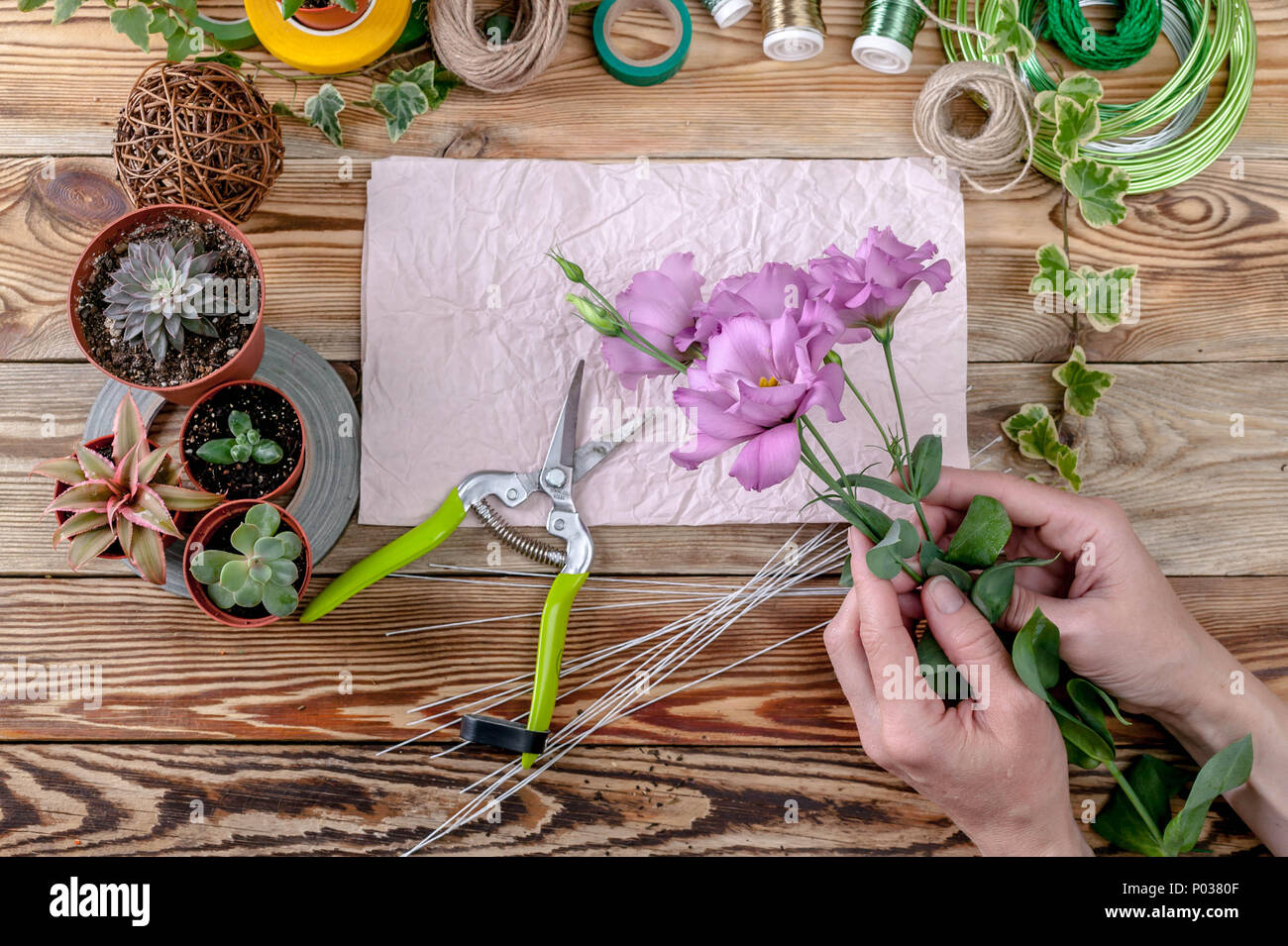 The florist's hands make a bouquet of flowers. People behind the work concept Top view Stock Photo