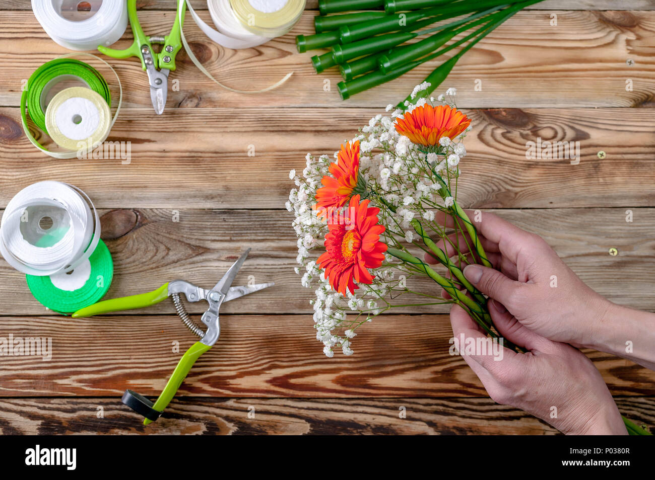 The florist's hands make a bouquet of flowers. People behind the work concept Top view Stock Photo