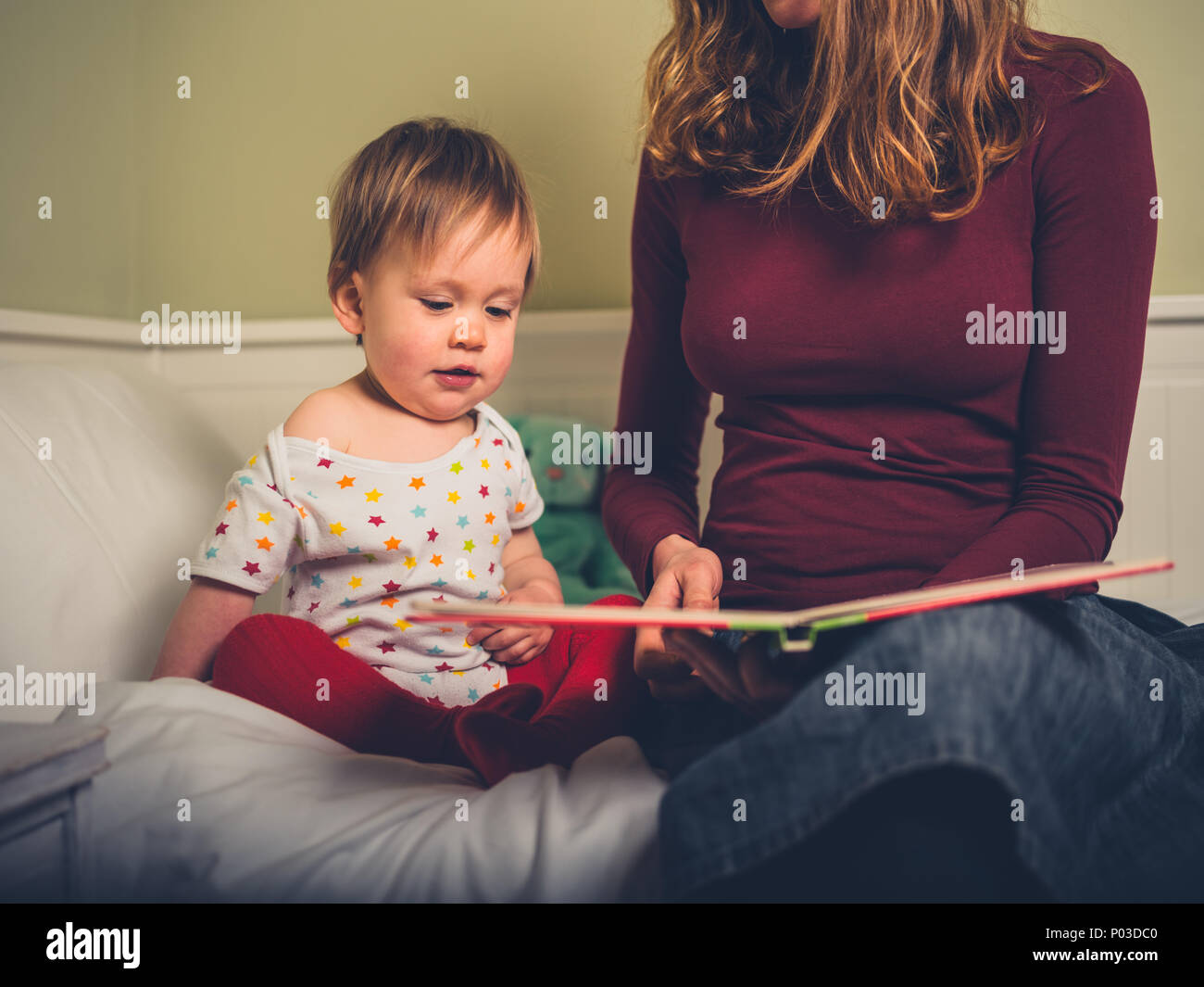 A young mother is reading a bedtime story to her little boy Stock Photo